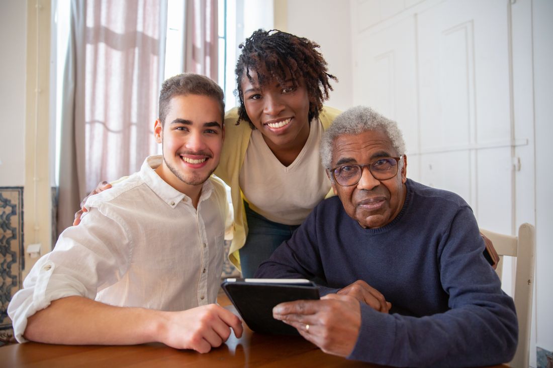 Familia sonriente acompañando a un adulto mayor mientras revisan información juntos